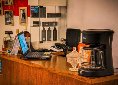 Área de recepción en Pelizzari Barbershop - Parque Patricios, Buenos Aires, con cafetera y laptop sobre el mostrador.