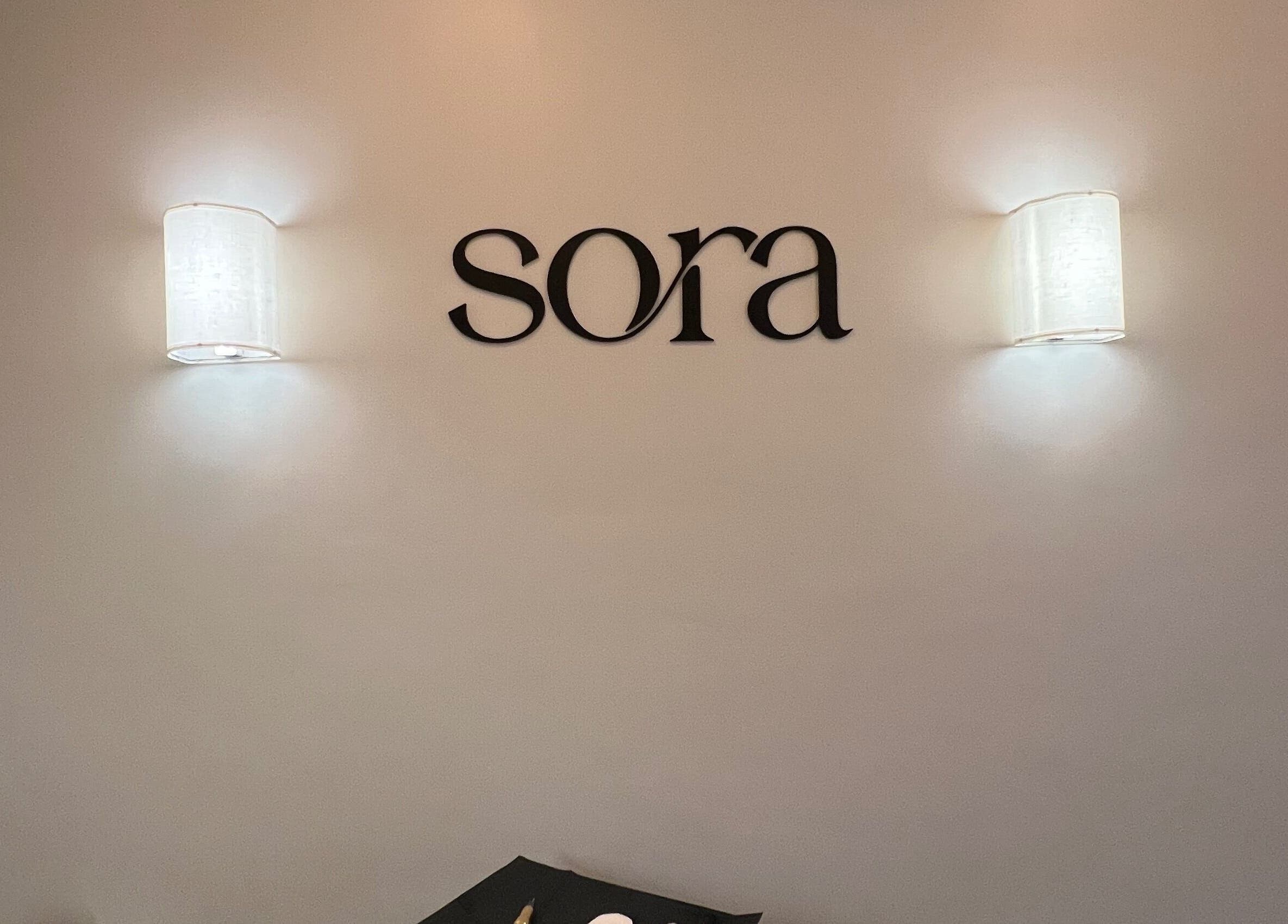 Elegant wall lights and Sora logo at Cole Bay, SX beauty and wellness venue.