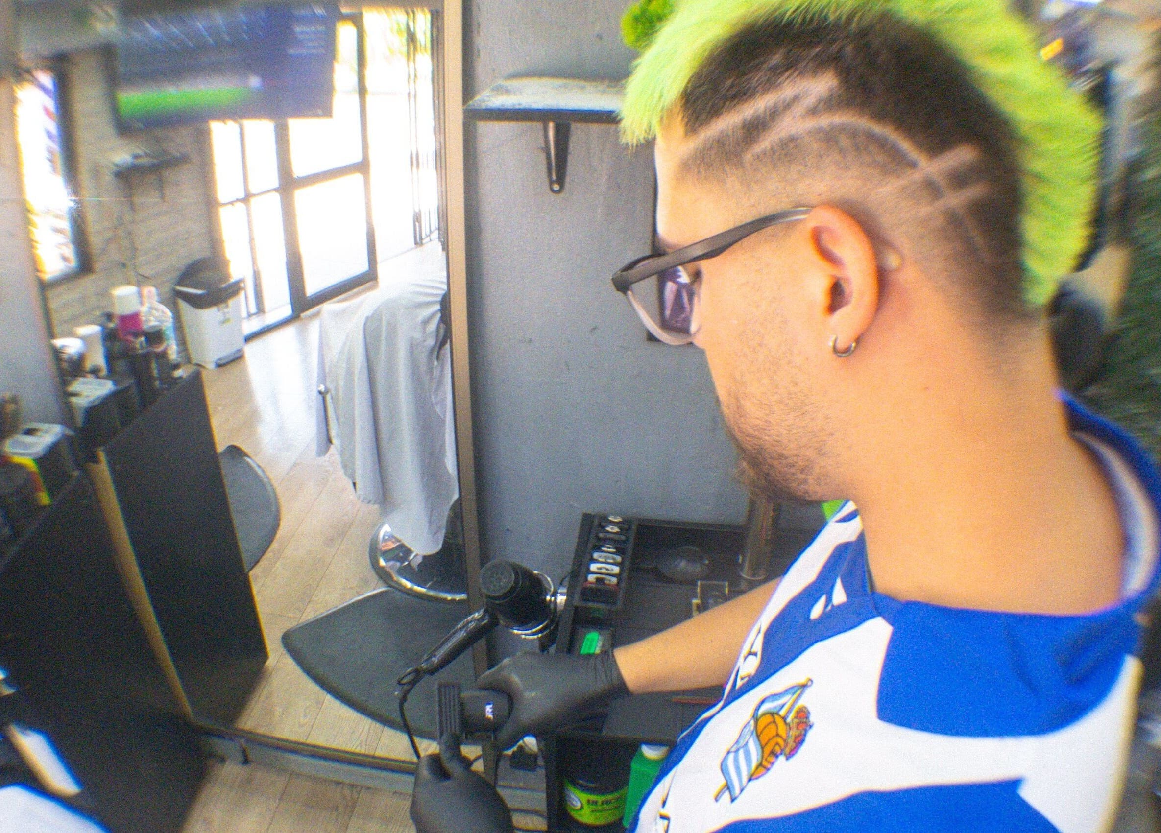 Barbero estilizando cabello en Ramses Barber, Peñalolén, Región Metropolitana, CL. Interior moderno y detallado.