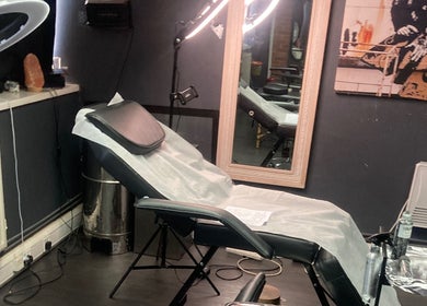Modern tattoo studio interior at MJ ink tattoos in Barking, England, GB featuring a comfortable chair and mirror.