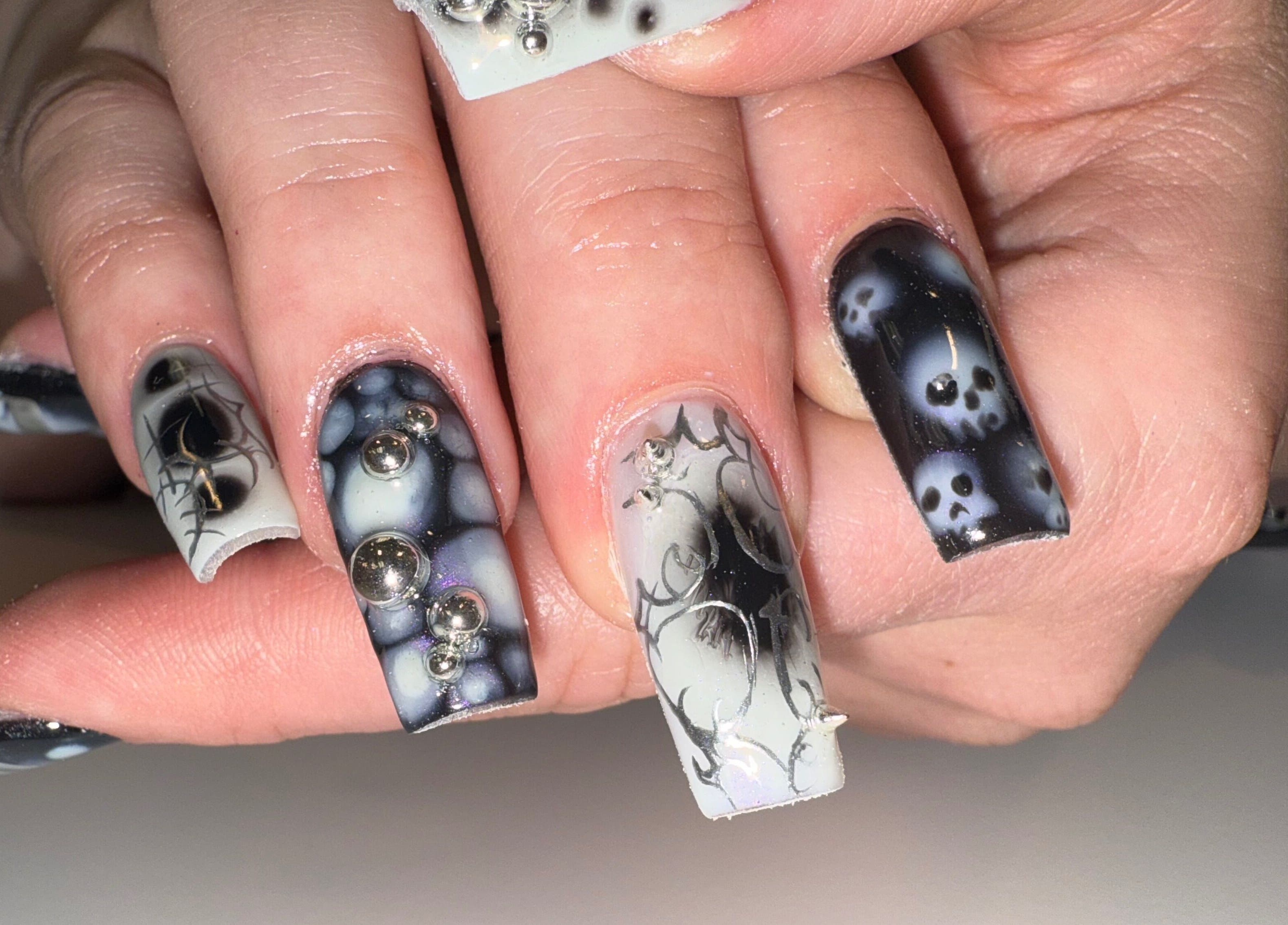 Unique black and white nail design from Squid Nails in Coquitlam, British Columbia, CA featuring skull patterns.