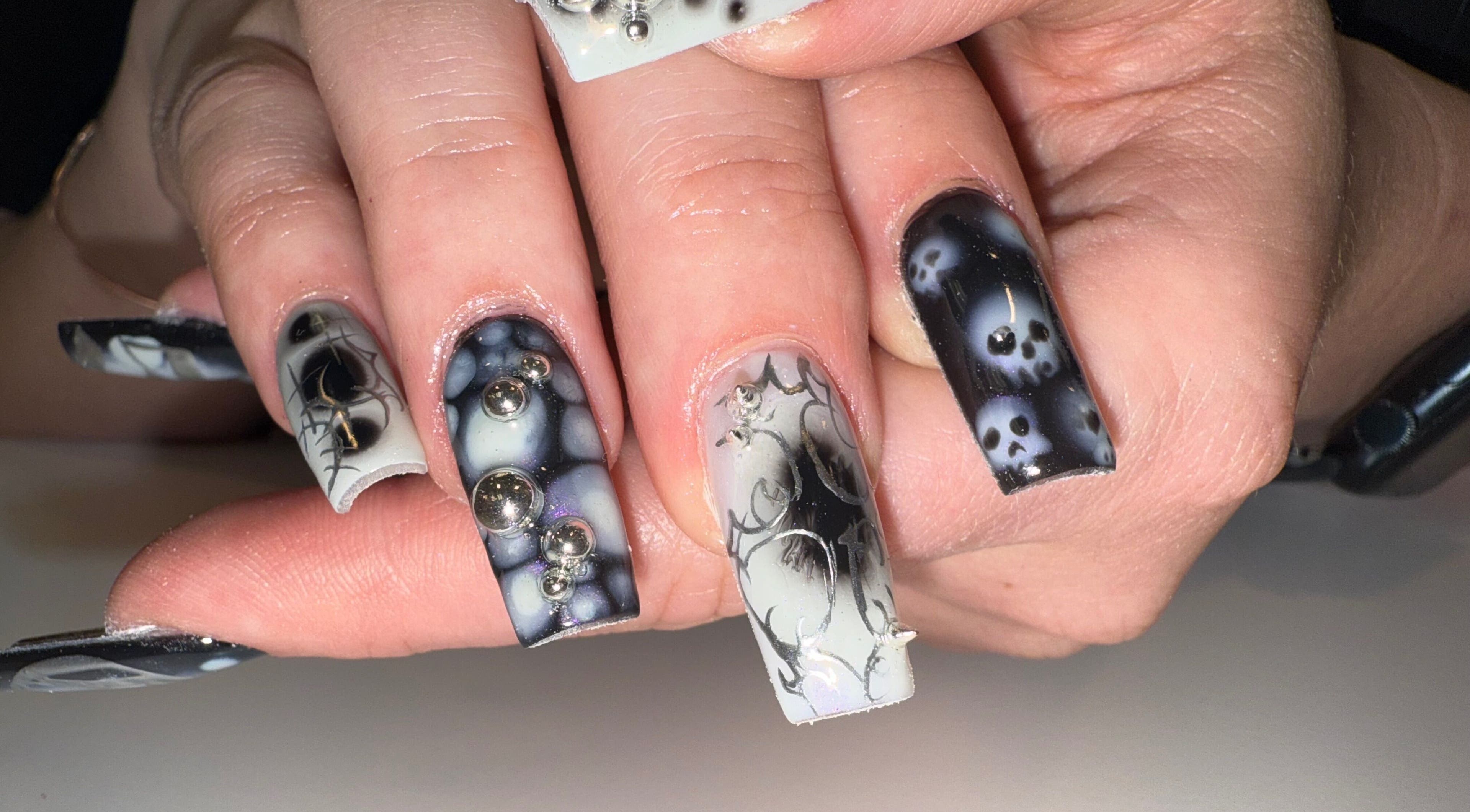 Unique black and white nail design from Squid Nails in Coquitlam, British Columbia, CA featuring skull patterns.