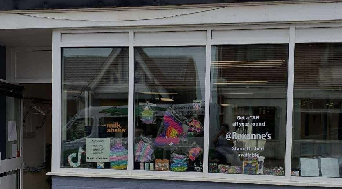 Street view of CaraEvans_Hair salon in Milford Haven, Wales, GB showcasing colorful product displays.