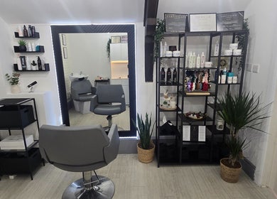 Inside Vega Complete Hair Care, Durham, England, GB. Modern salon with grey chairs, products on shelves, and plants.