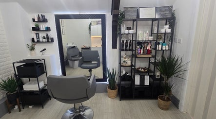 Inside Vega Complete Hair Care, Durham, England, GB. Modern salon with grey chairs, products on shelves, and plants.