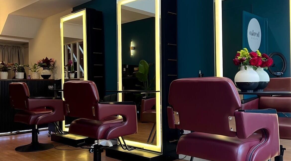 Elegant salon interior at Henko Studio, London, England, GB, featuring plush chairs and illuminated mirrors.