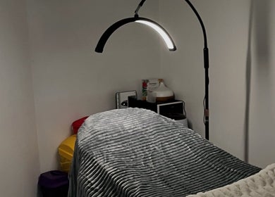 Cozy treatment room at Ella’s Beauty Lounge, Briercliffe, England, GB, featuring soft lighting and plush bedding.