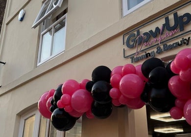 Front entrance of Glow Up Tanning & Beauty Downham, Downham Market, England, GB, with pink and black balloons.