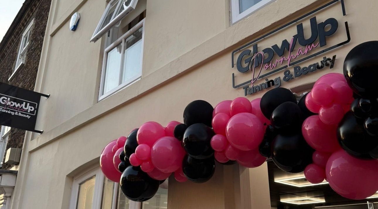 Front entrance of Glow Up Tanning & Beauty Downham, Downham Market, England, GB, with pink and black balloons.