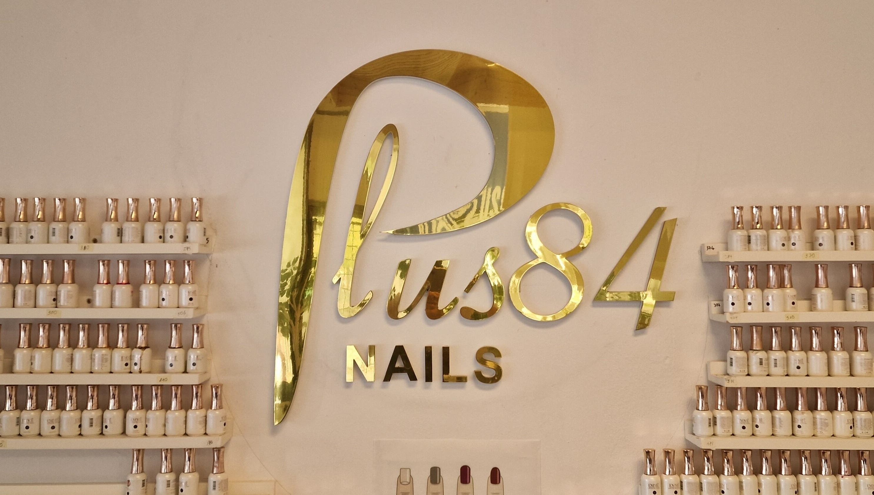Elegant guldskyltning av Plus 84 Nails i Landskrona, Skåne Län, SE med poler vid vägg.