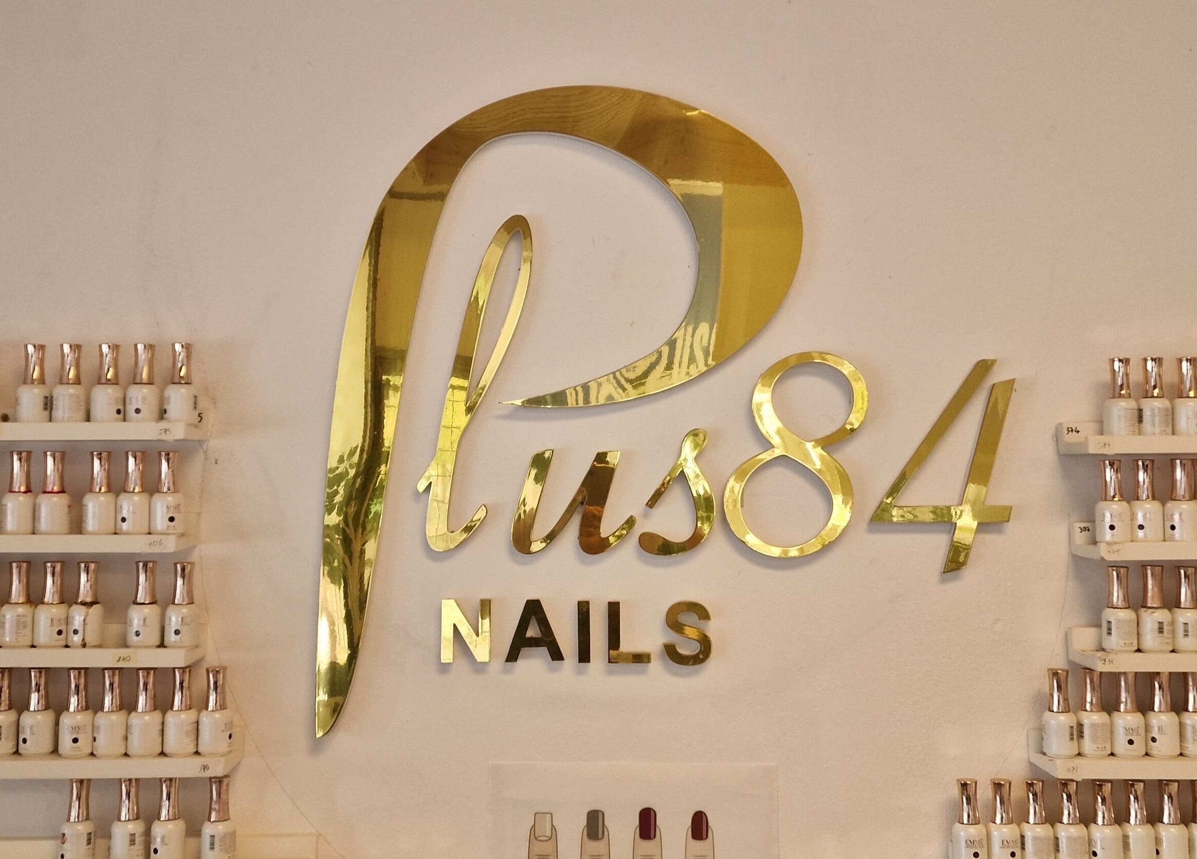 Elegant guldskyltning av Plus 84 Nails i Landskrona, Skåne Län, SE med poler vid vägg.