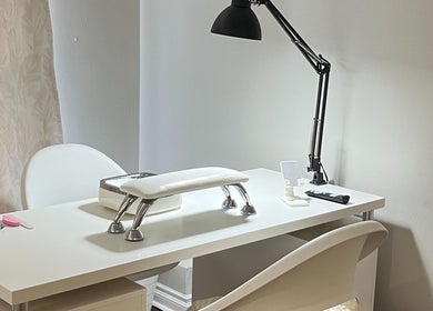 Modern nail station at NailedbyNehita in Toronto, Ontario, CA, featuring a sleek white manicure table and lamp.