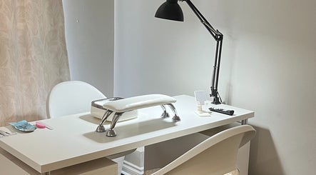 Modern nail station at NailedbyNehita in Toronto, Ontario, CA, featuring a sleek white manicure table and lamp.