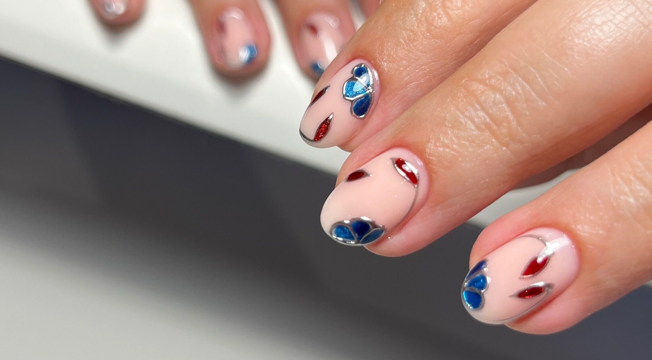 Close-up of vibrant blue and red nail art at Nailedby Nehita, Toronto, Ontario, CA.