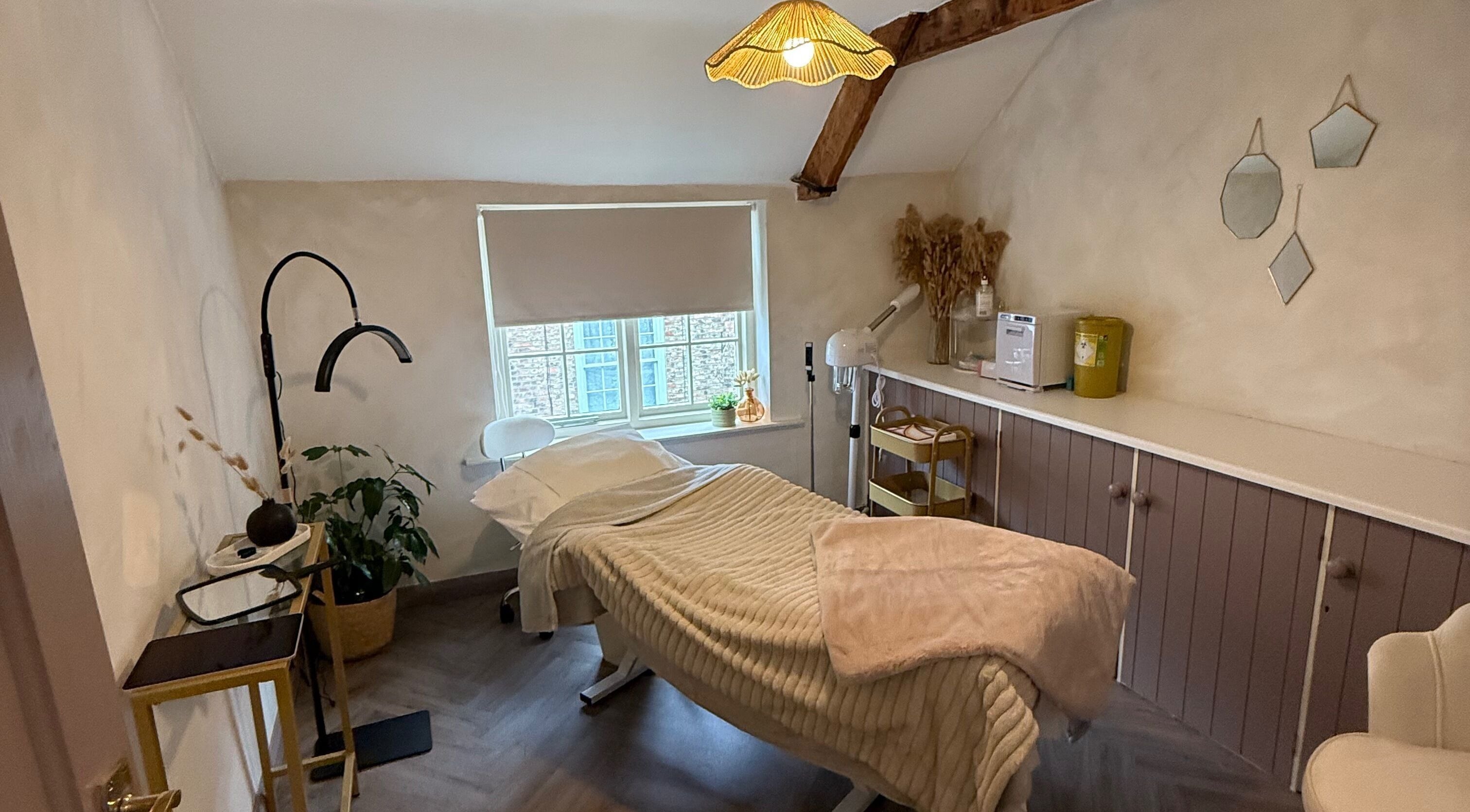 Relaxing treatment room at Bare and Glow Skin, Ripon, England, GB with warm decor and a treatment bed.