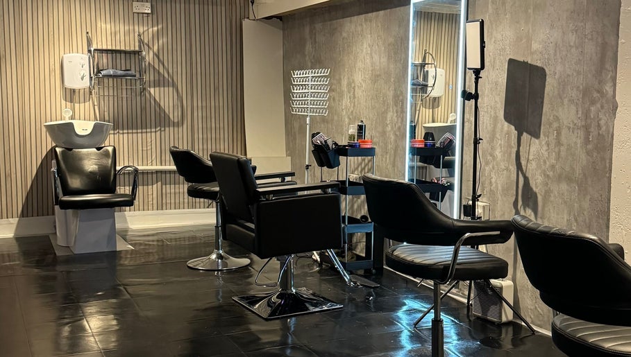 Modern hair salon interior at Hairslayedbydee, Manchester, England, GB with sleek black styling chairs.