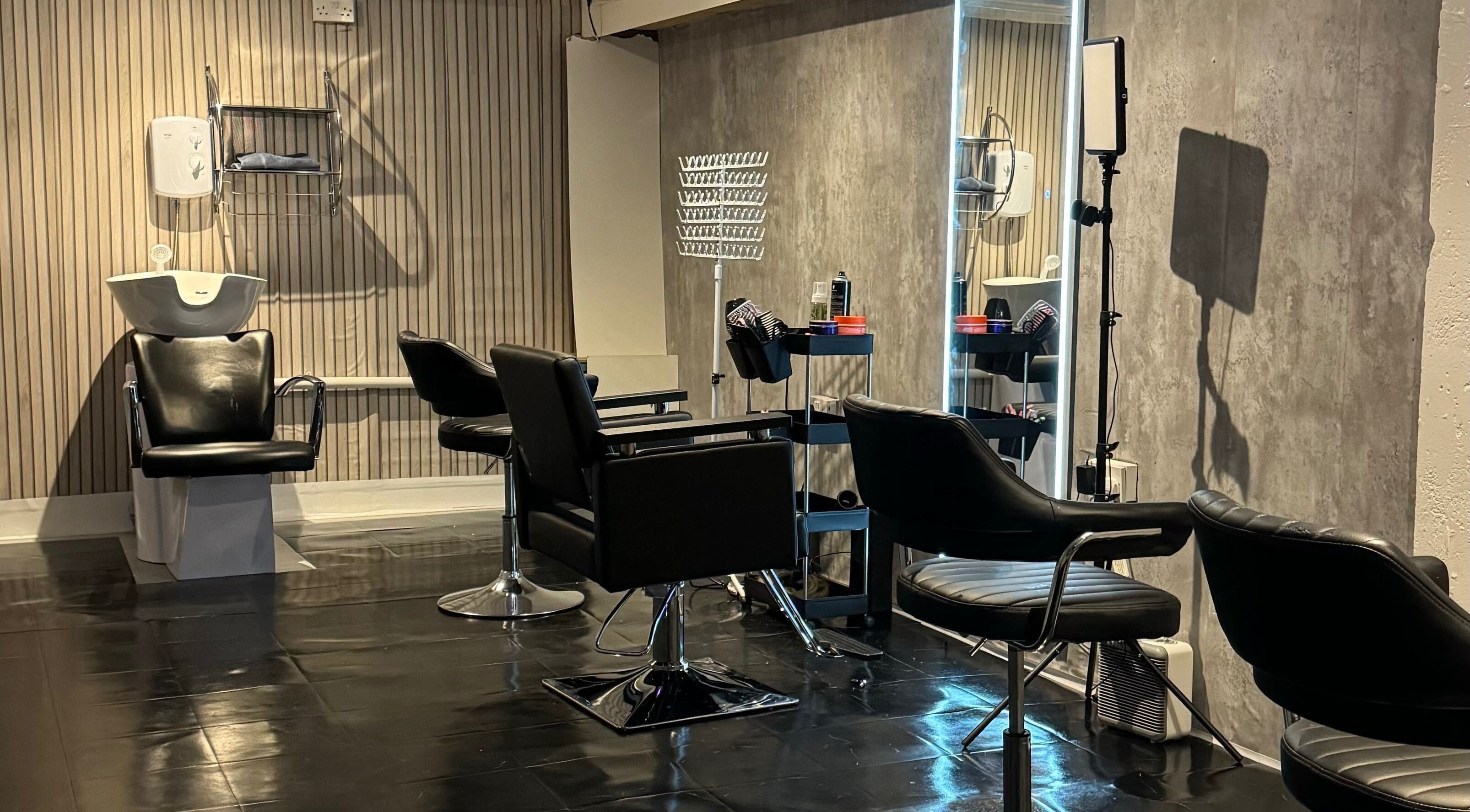 Modern hair salon interior at Hairslayedbydee, Manchester, England, GB with sleek black styling chairs.
