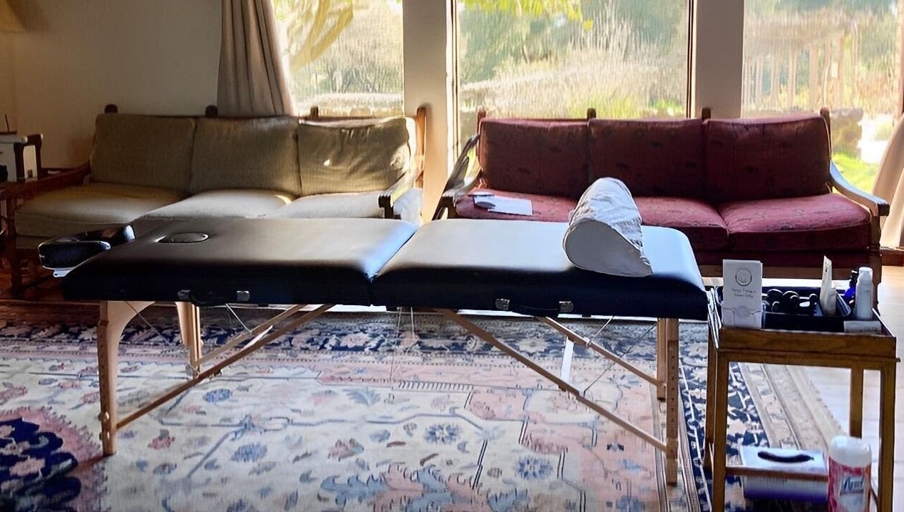 Massage table in a serene room at Therapeutic Touch, Sonoma, California, US, with cozy couches and natural light.