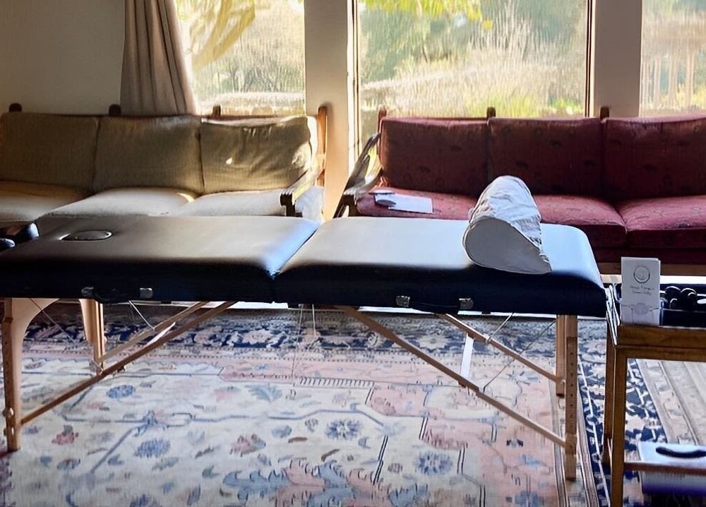 Massage table in a serene room at Therapeutic Touch, Sonoma, California, US, with cozy couches and natural light.