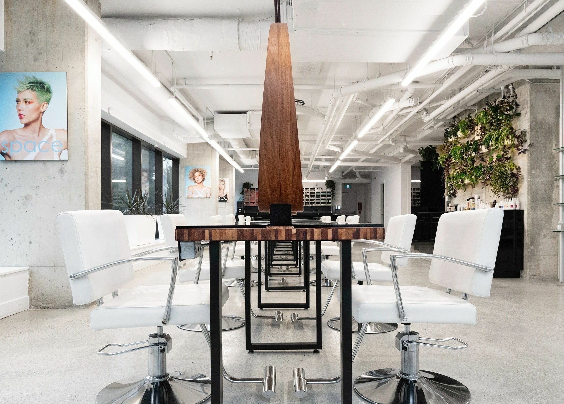 Space Salon - Vancouver features chic, white salon chairs and a lush plant wall in Vancouver, British Columbia, CA.