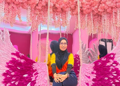 Woman at Barbie Lash Empire in Kuala Lumpur, surrounded by pink florals and angel wings decor.