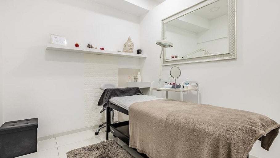A tranquil treatment room at Junique Nails, Vigo, ES, featuring a relaxing massage table and a large mirror.