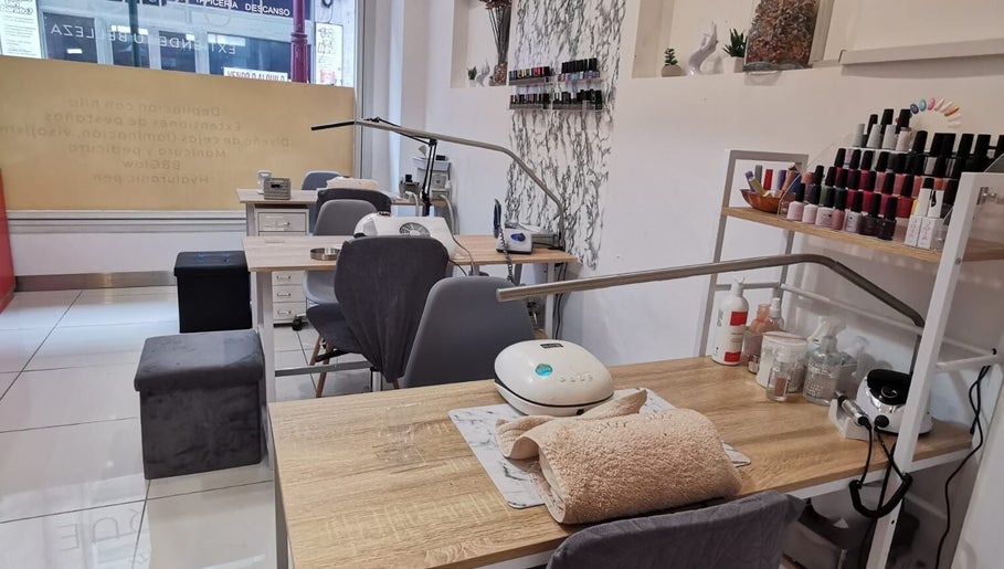 Mesa de servicio en Junique Nails, Vigo, ES, con herramientas de manicura y esmaltes exhibidos.