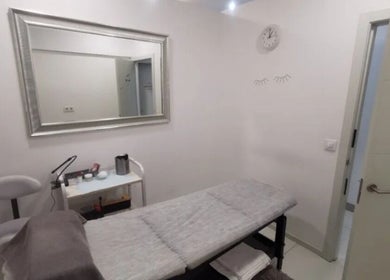 Sala de tratamiento en Junique Nails, Vigo, ES, con camilla y espejo elegante.