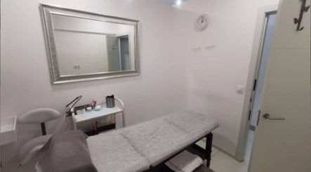 Sala de tratamiento en Junique Nails, Vigo, ES, con camilla y espejo elegante.