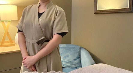 Therapist at Orenda Day Spa in Hobart, Tasmania, AU, standing beside a cozy massage table in a peaceful room.