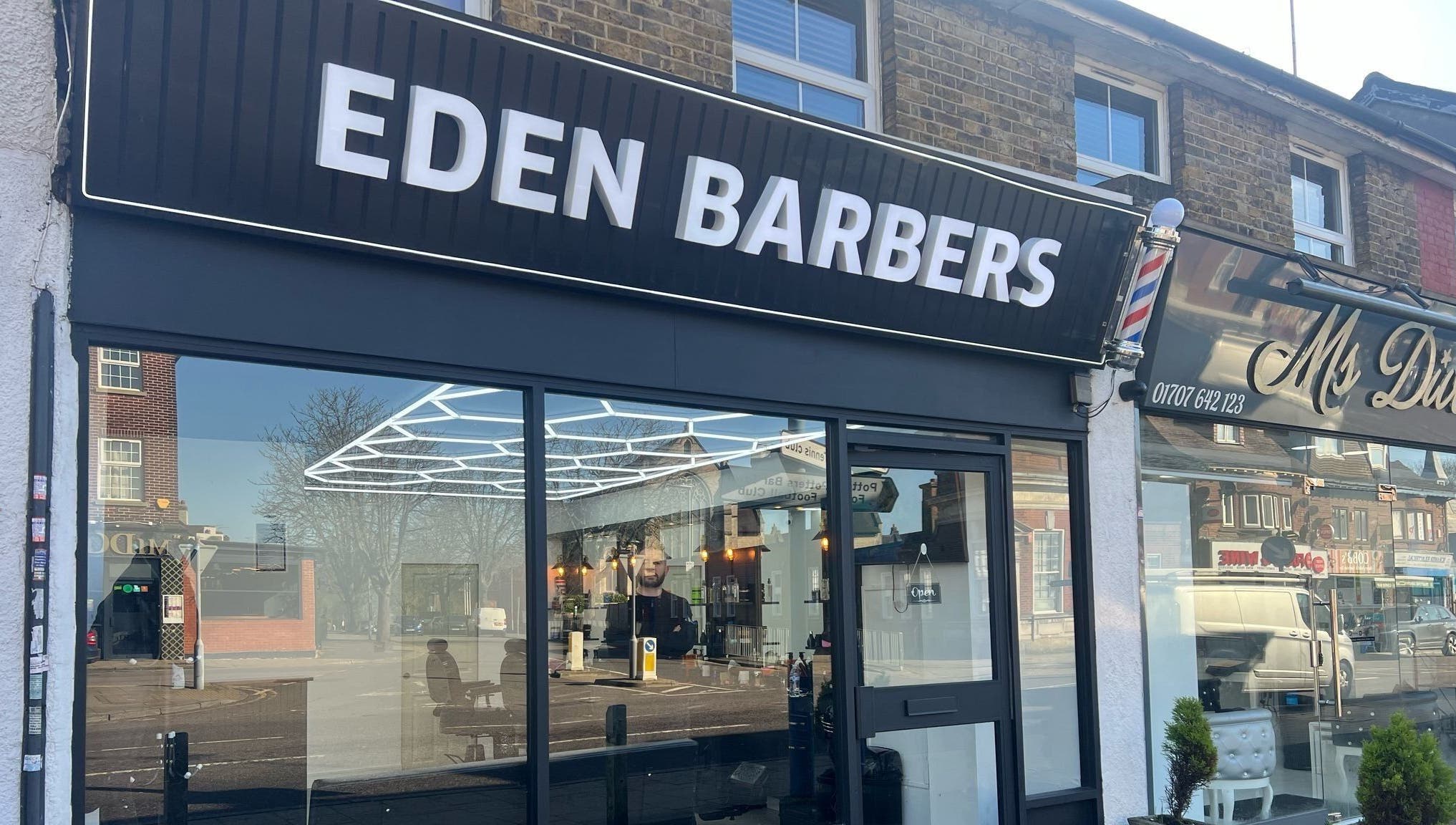 Eden Barbers shopfront in Potters Bar, England, showcasing sleek modern design and inviting entrance.