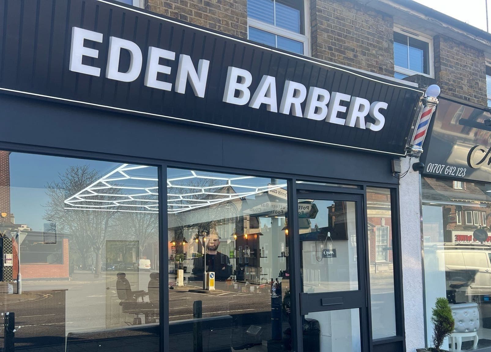 Eden Barbers shopfront in Potters Bar, England, showcasing sleek modern design and inviting entrance.