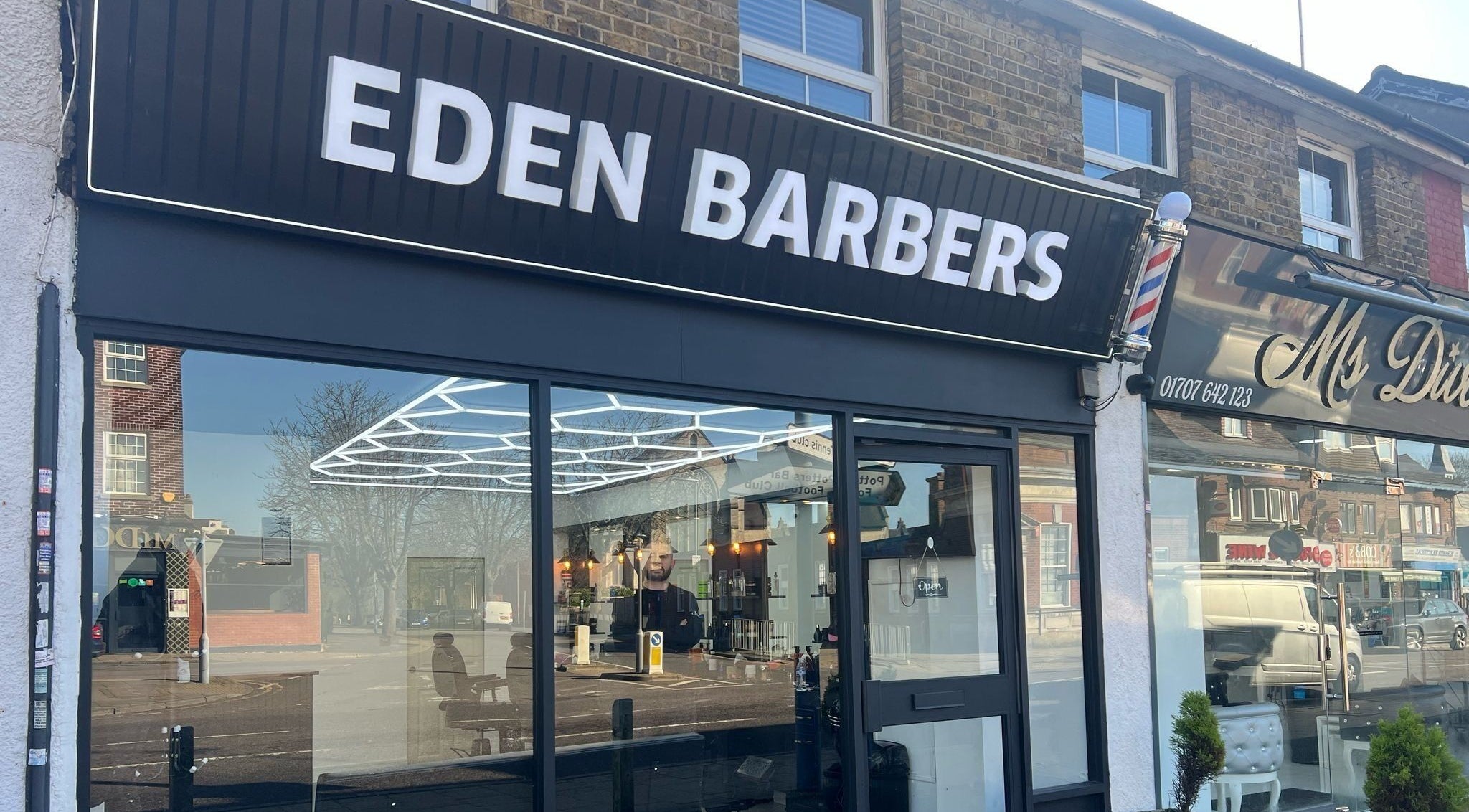 Eden Barbers shopfront in Potters Bar, England, showcasing sleek modern design and inviting entrance.