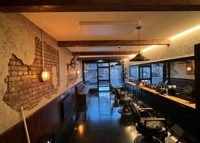 Cozy interior of EAST FINCHLEY BARBERS in London, England, GB, featuring exposed brick walls and barber chairs.