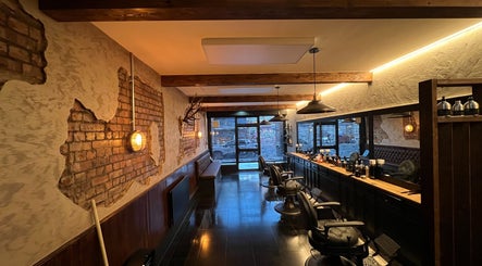 Cozy interior of EAST FINCHLEY BARBERS in London, England, GB, featuring exposed brick walls and barber chairs.