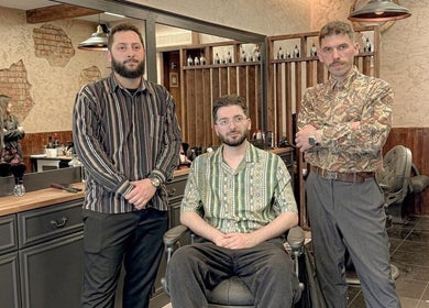Three barbers at EAST FINCHLEY BARBERS in London, England, GB, showcasing stylish interiors.