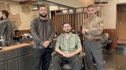 Three barbers at EAST FINCHLEY BARBERS in London, England, GB, showcasing stylish interiors.