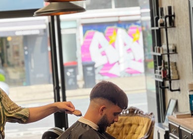 Barber at EAST FINCHLEY BARBERS in London, England, GB, expertly styling a client's hair.