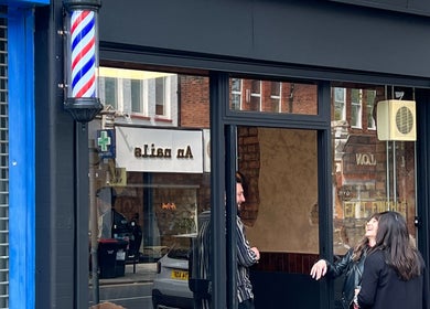 Front view of EAST FINCHLEY BARBERS in London, England, GB with iconic barber pole and sleek exterior.