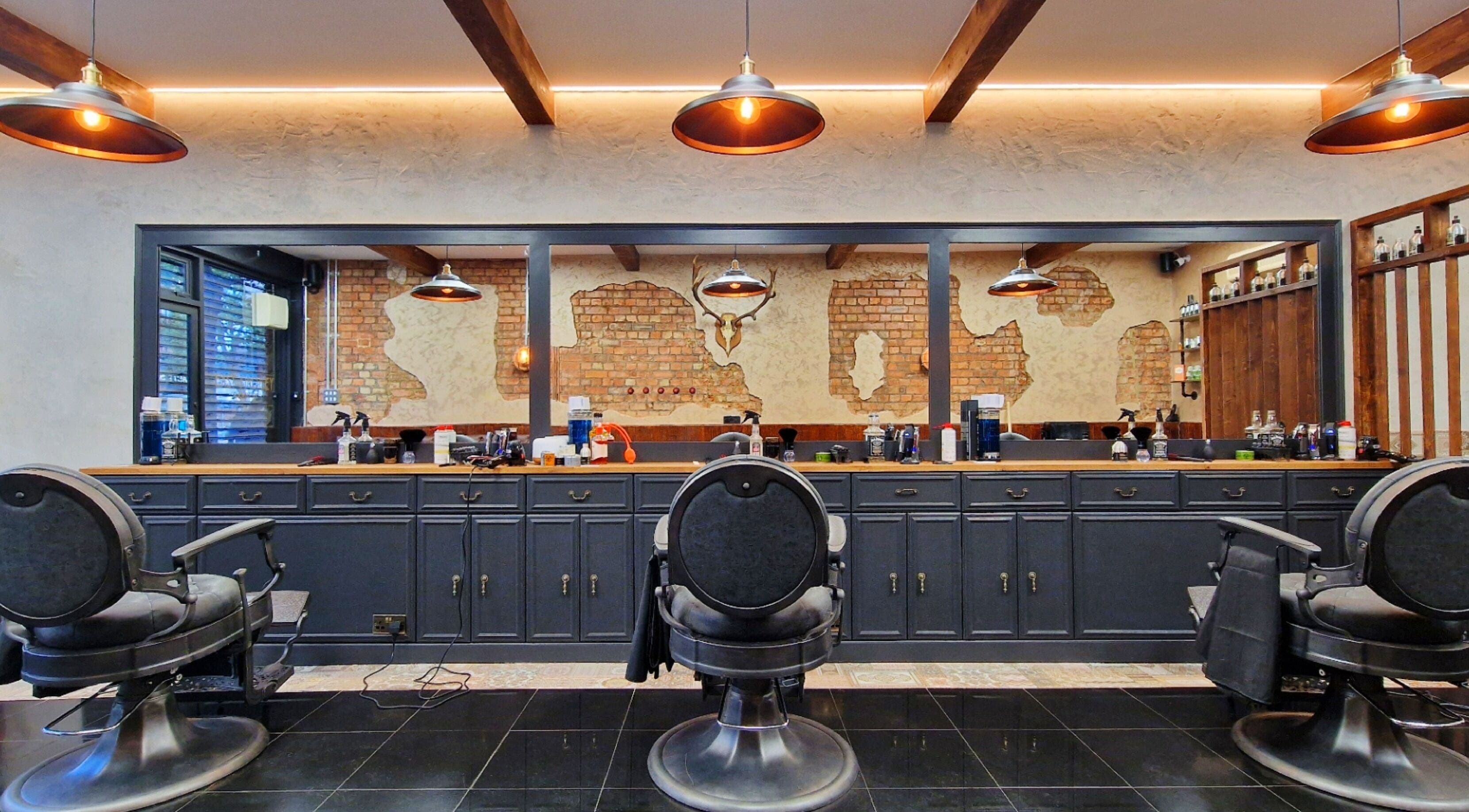 Stylish interior of EAST FINCHLEY BARBERS with vintage chairs and exposed brick in London, England, GB.