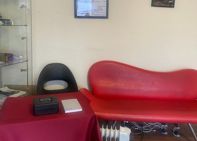Cozy lounge area at Replay Massage, Cardiff, Wales, GB with modern red sofa and glass shelves.