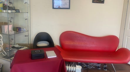 Cozy lounge area at Replay Massage, Cardiff, Wales, GB with modern red sofa and glass shelves.