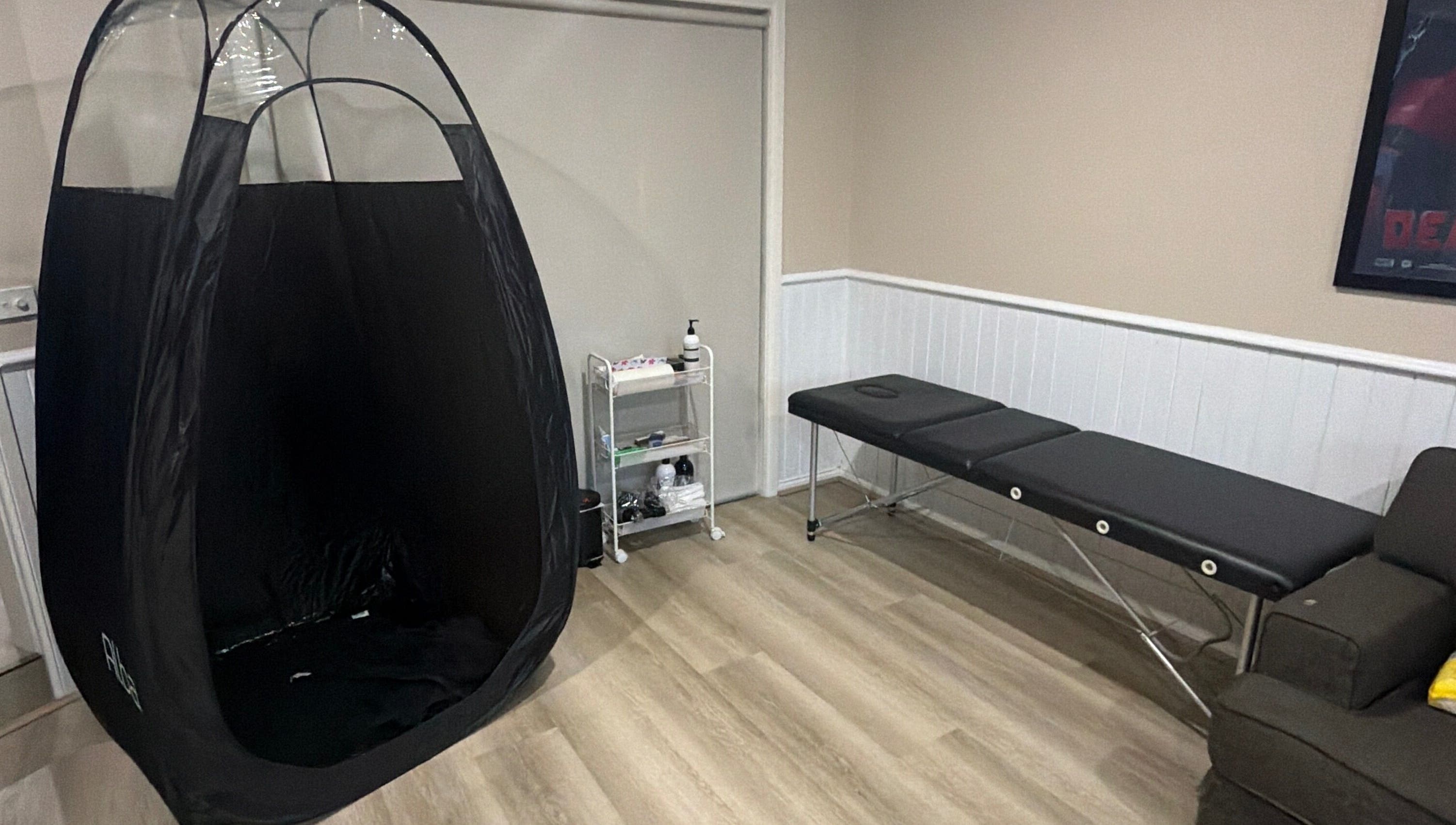 Relaxing tanning area at Sprayedbyizz, Narre Warren South, Victoria, AU, featuring a tanning tent and massage table.