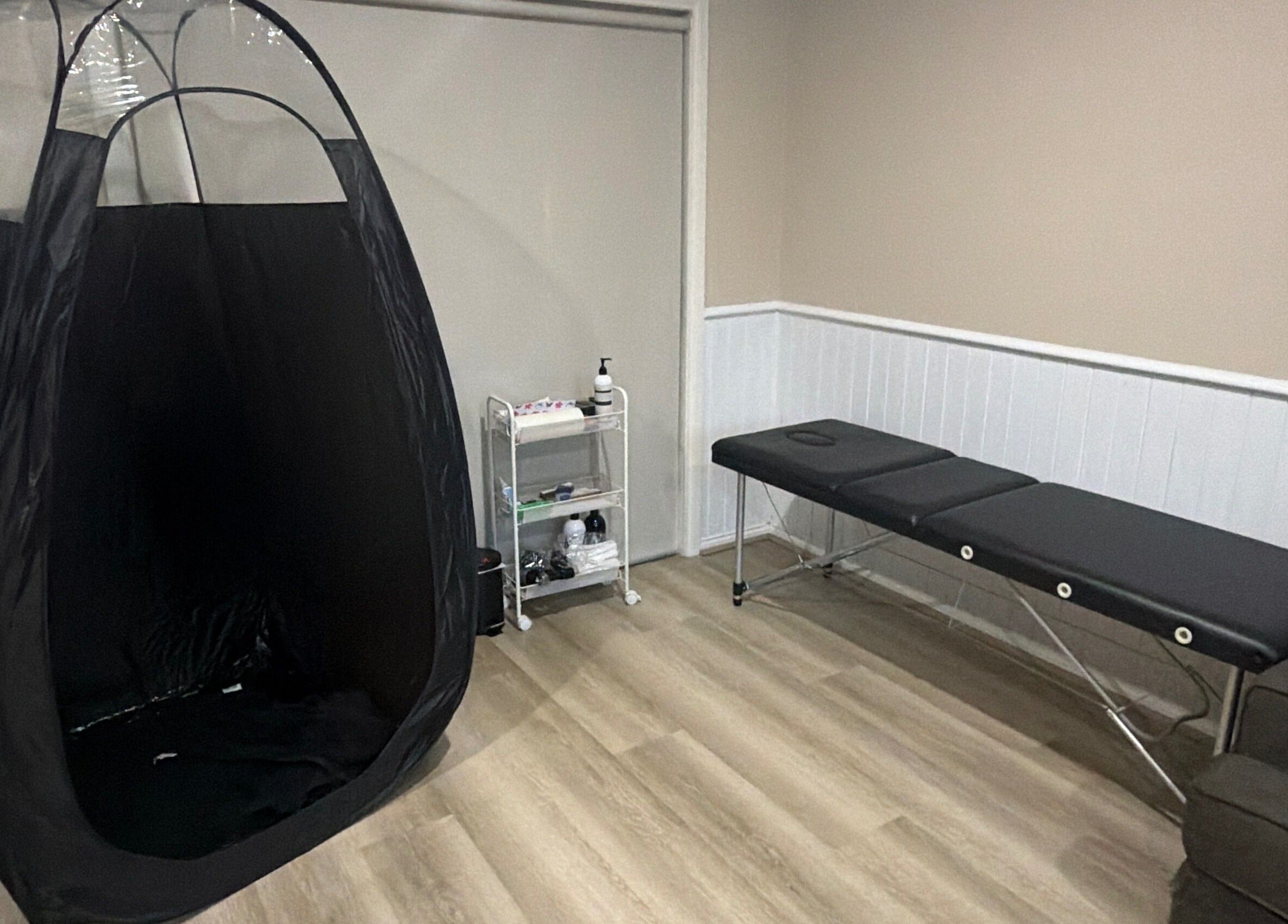 Relaxing tanning area at Sprayedbyizz, Narre Warren South, Victoria, AU, featuring a tanning tent and massage table.
