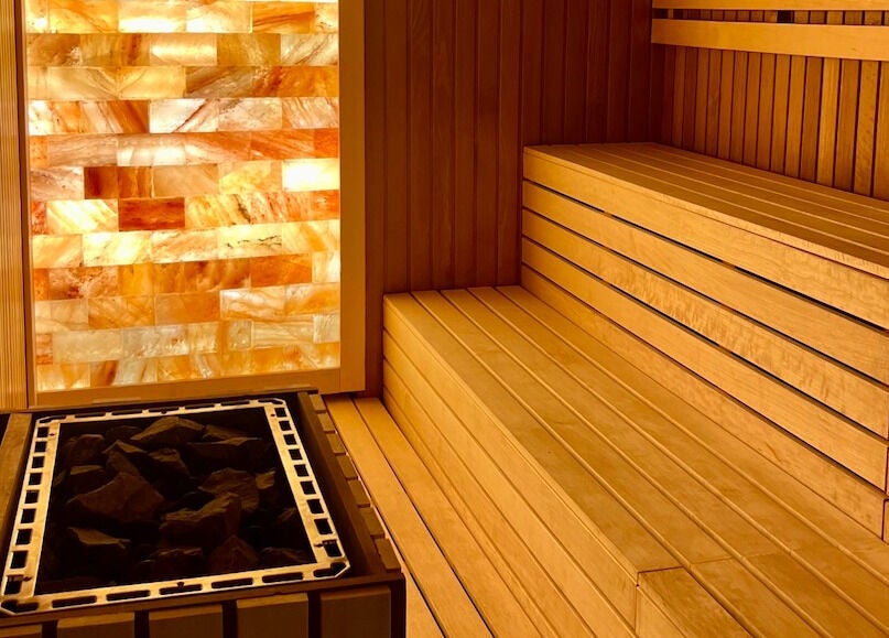 Warm wooden sauna at Naturelife Spa Marina Abu Dhabi, Abu Dhabi, AE, featuring glowing salt wall.