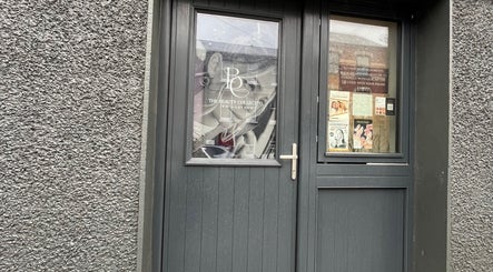 Front entrance of The Beauty Collective in Cork, County Cork, IE, showcasing stylish design and promotional posters.