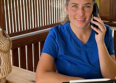 Medewerker bij El Fuego Pedicure en Manicure, Willemstad, CW, aan telefoon in houten spa-omgeving.
