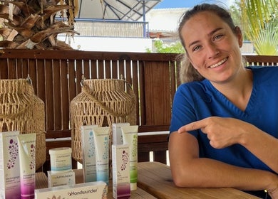 Medewerker bij El Fuego Pedicure en Manicure, Willemstad, CW toont verzorgingsproducten op een houten tafel.
