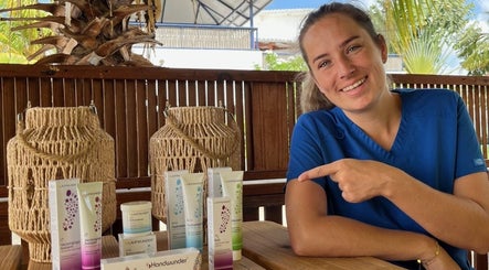 Medewerker bij El Fuego Pedicure en Manicure, Willemstad, CW toont verzorgingsproducten op een houten tafel.