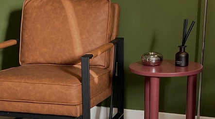 Cozy leather chair and chic table at June Studios, Edinburgh, Scotland, GB, offering inviting relaxation.